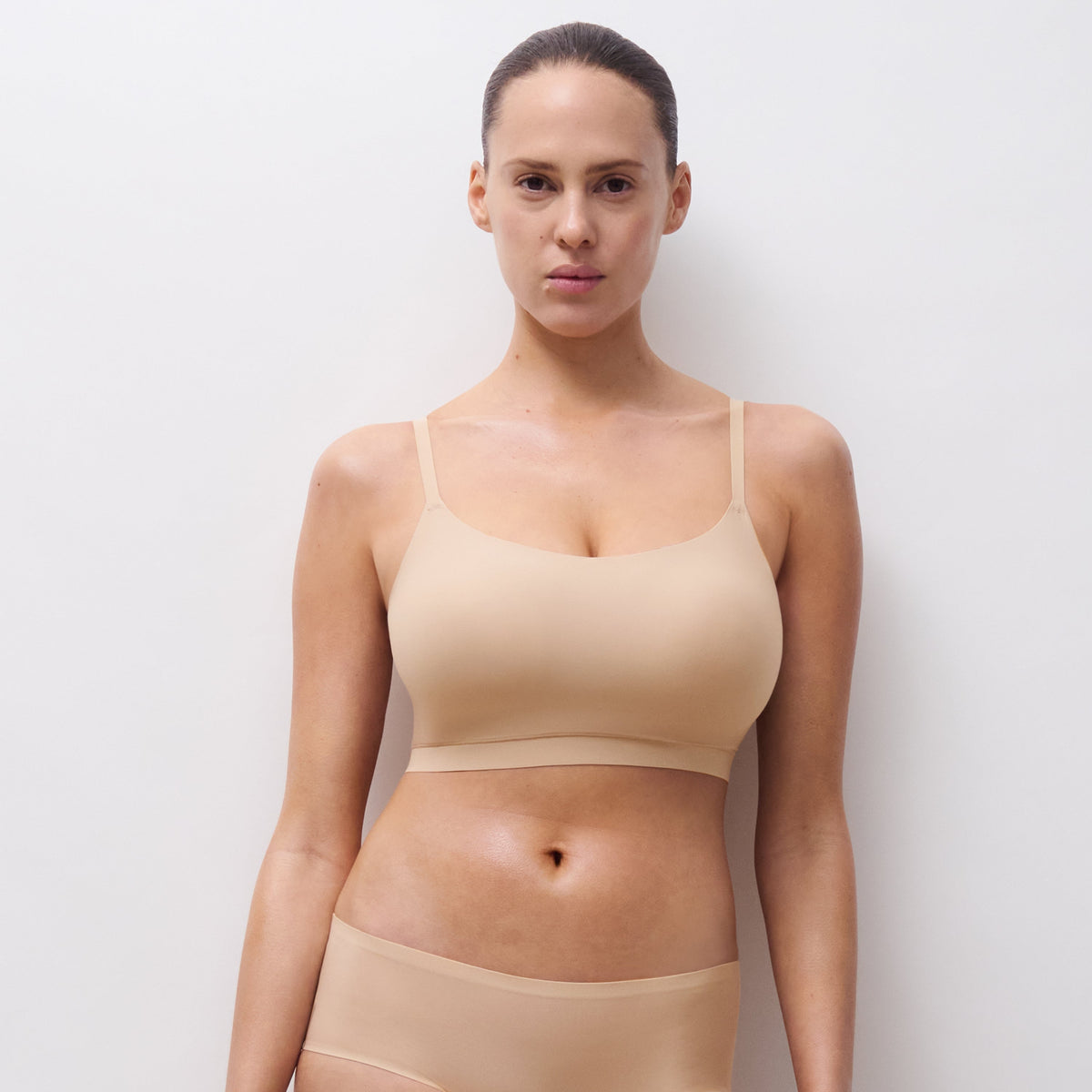 Woman wearing a beige bra and panties set against a plain background