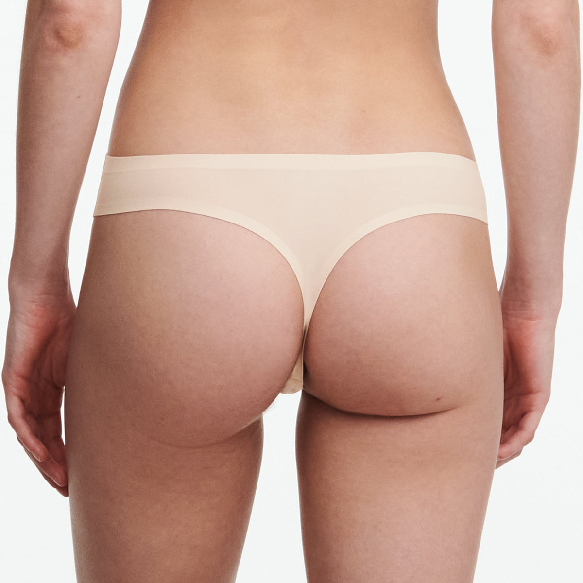 Beige thong worn by a person on a white background