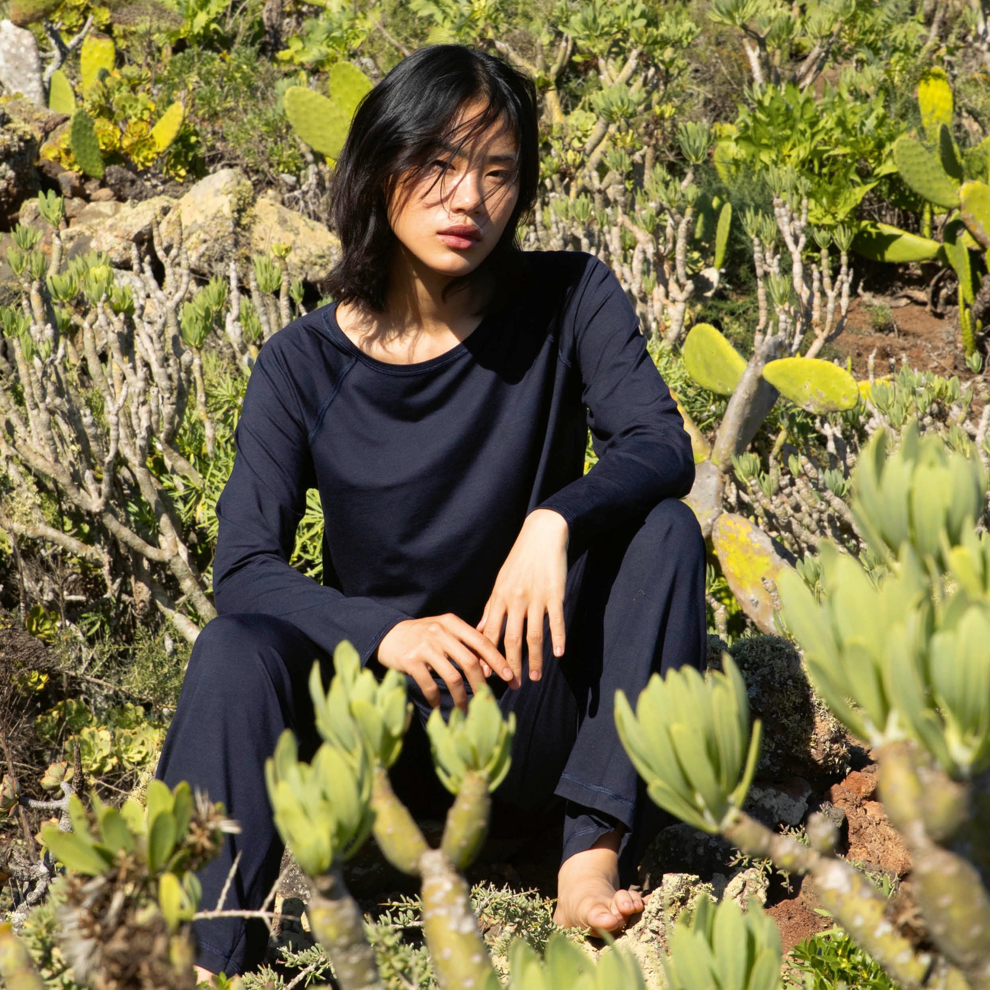 Person sitting among cacti and succulents in a natural setting
