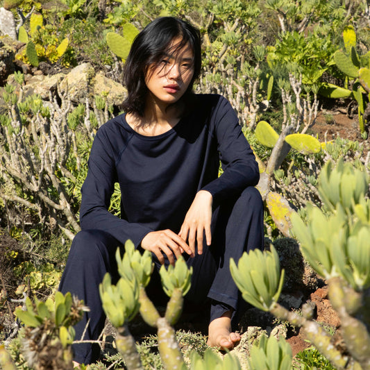 Person sitting among cacti and succulents in a natural setting