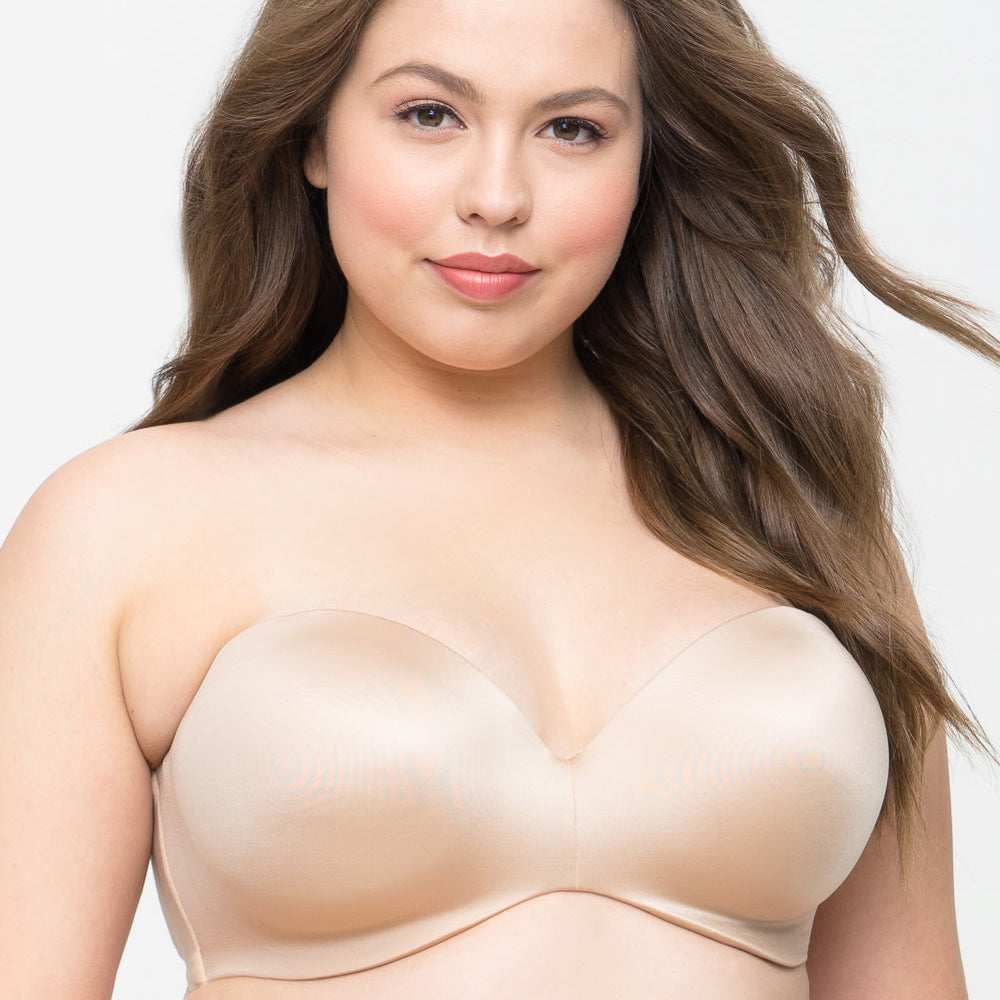 Woman wearing a beige strapless bra against a plain background