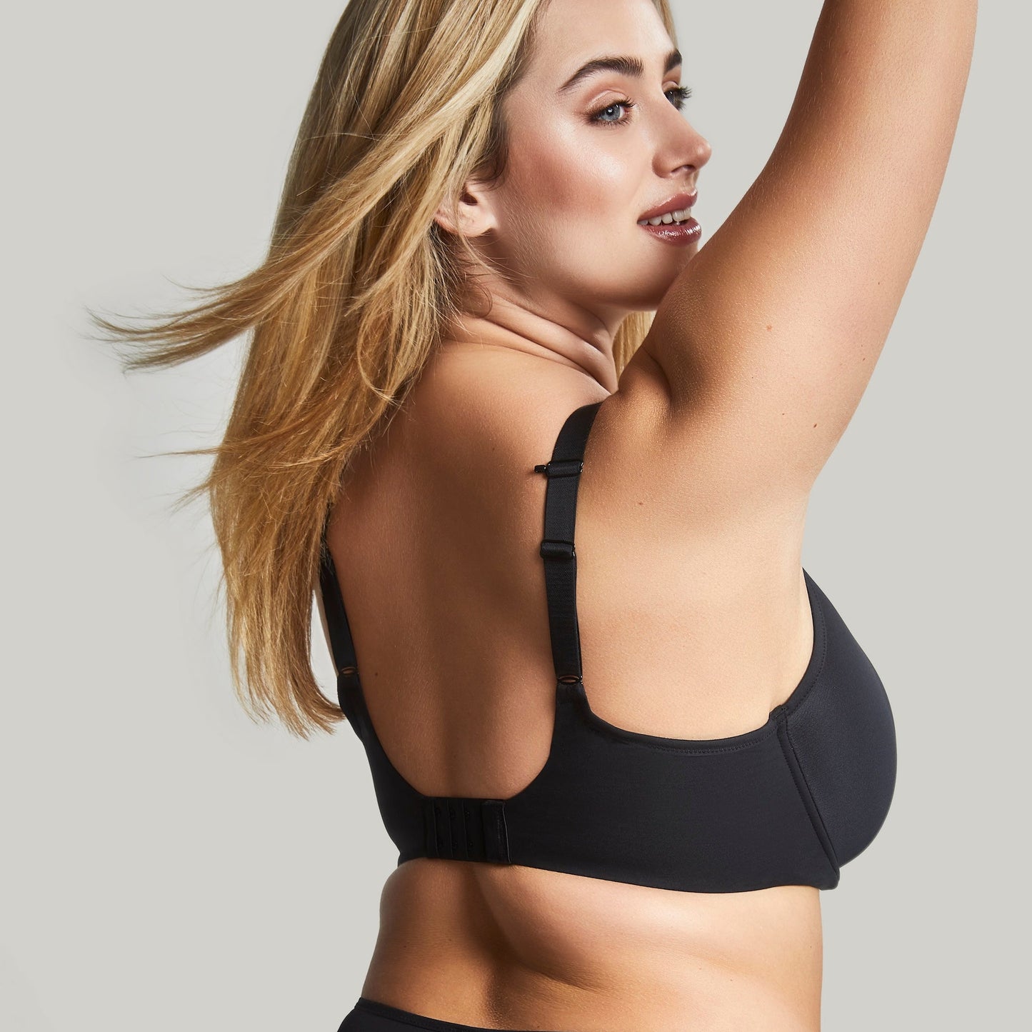 Woman wearing a black bra against a plain background