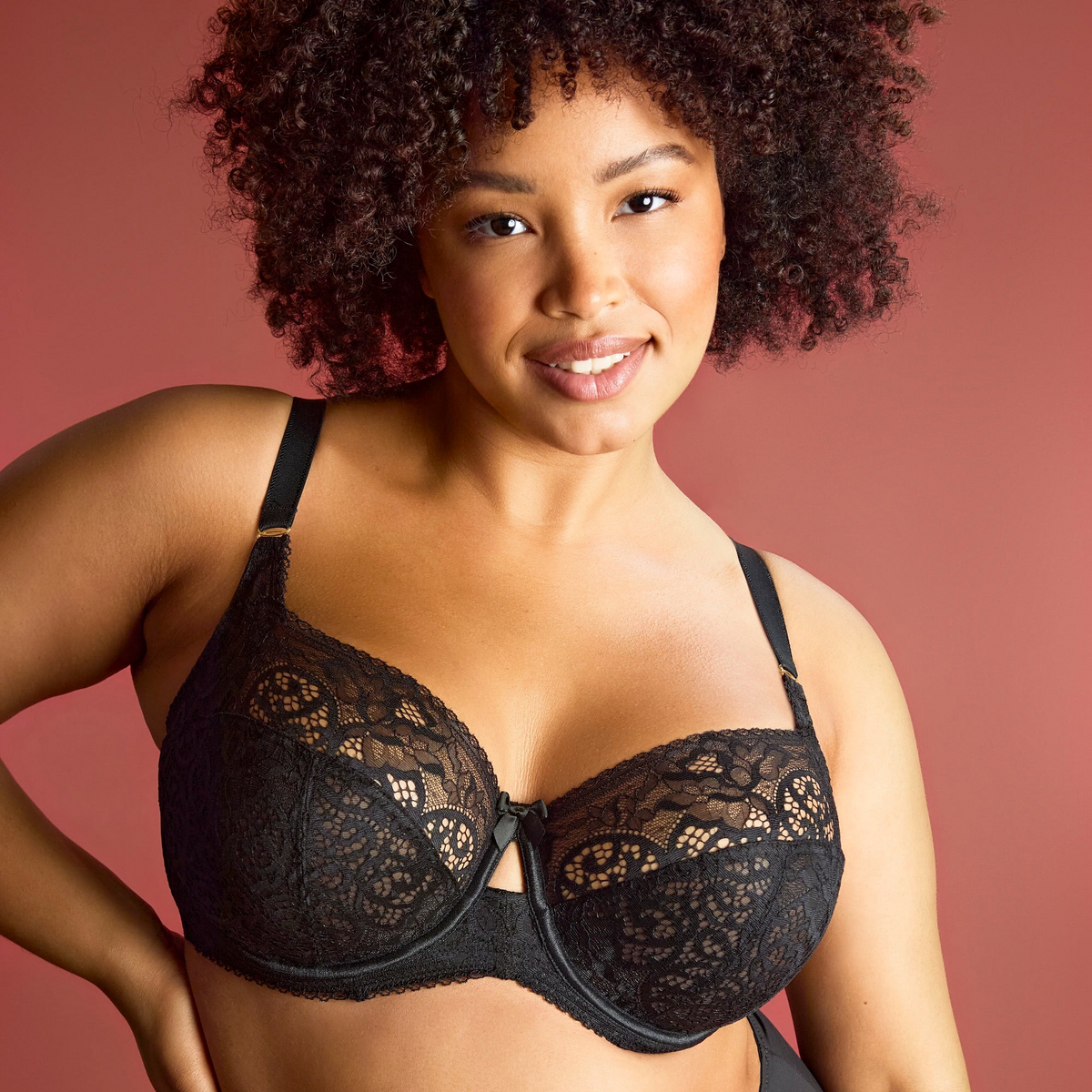 Woman wearing a black lace bra against a brown background