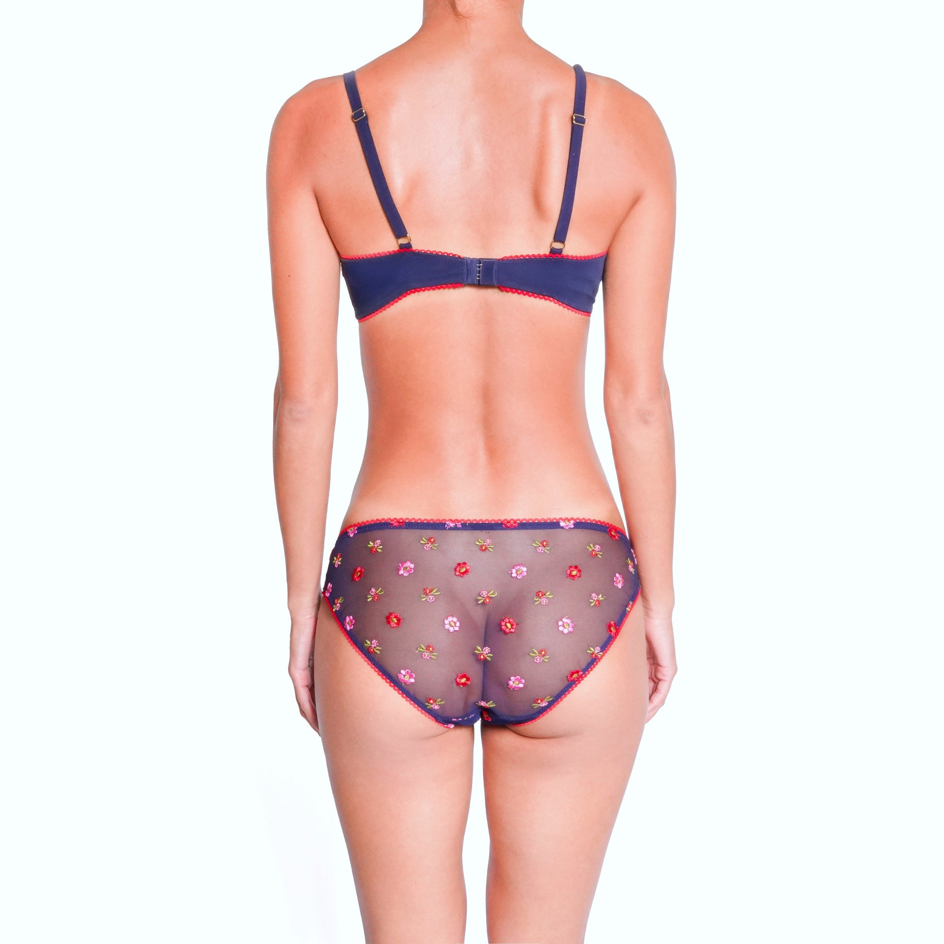 Woman wearing a navy blue bra and floral underwear on a white background