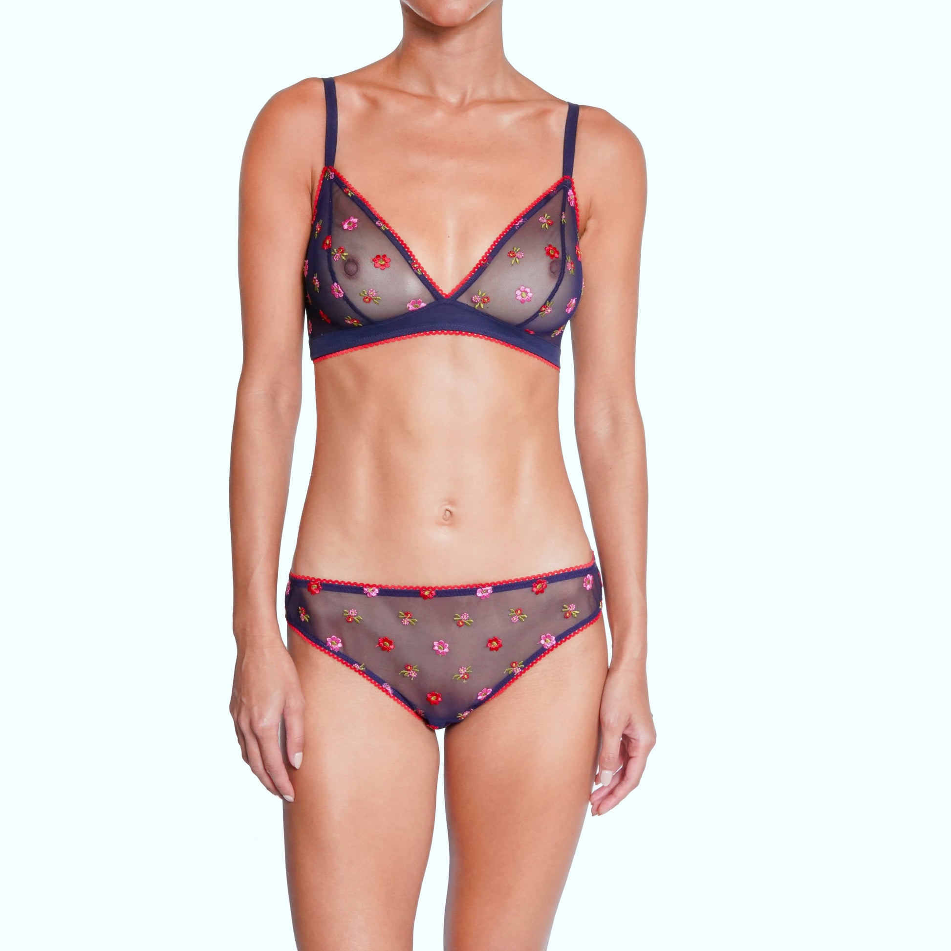 Woman wearing a navy blue lingerie set with floral details on a white background