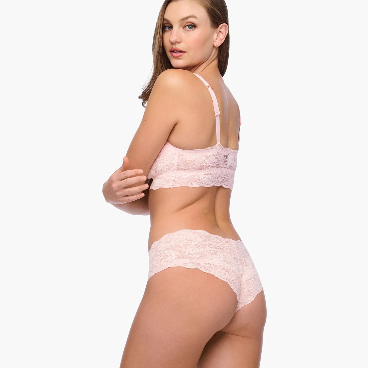 Woman wearing a pink lace lingerie set on a white background