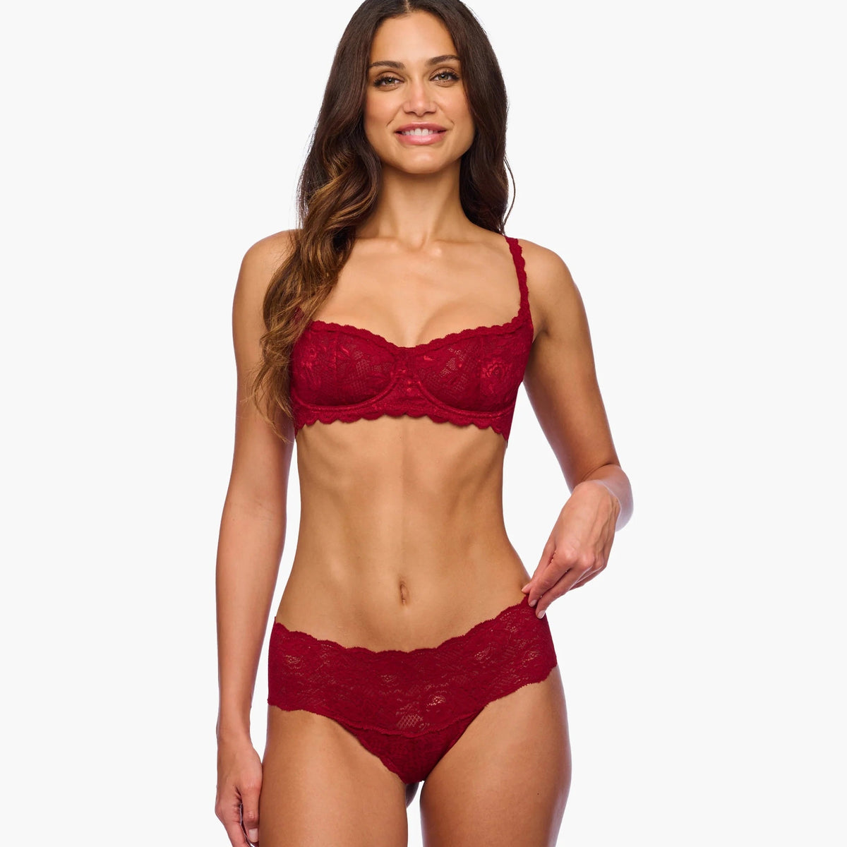 Woman wearing a red lace lingerie set on a white background