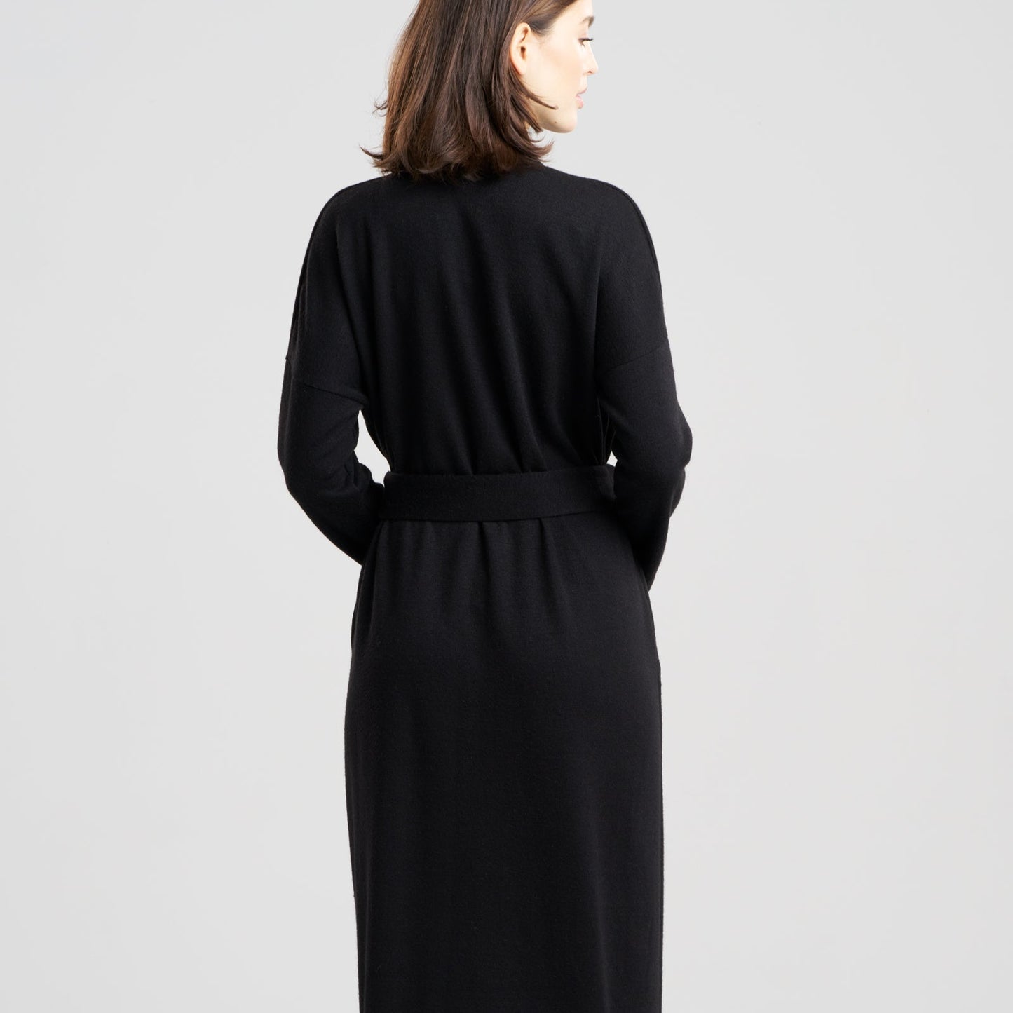 Woman wearing a black dress with a belt on a white background