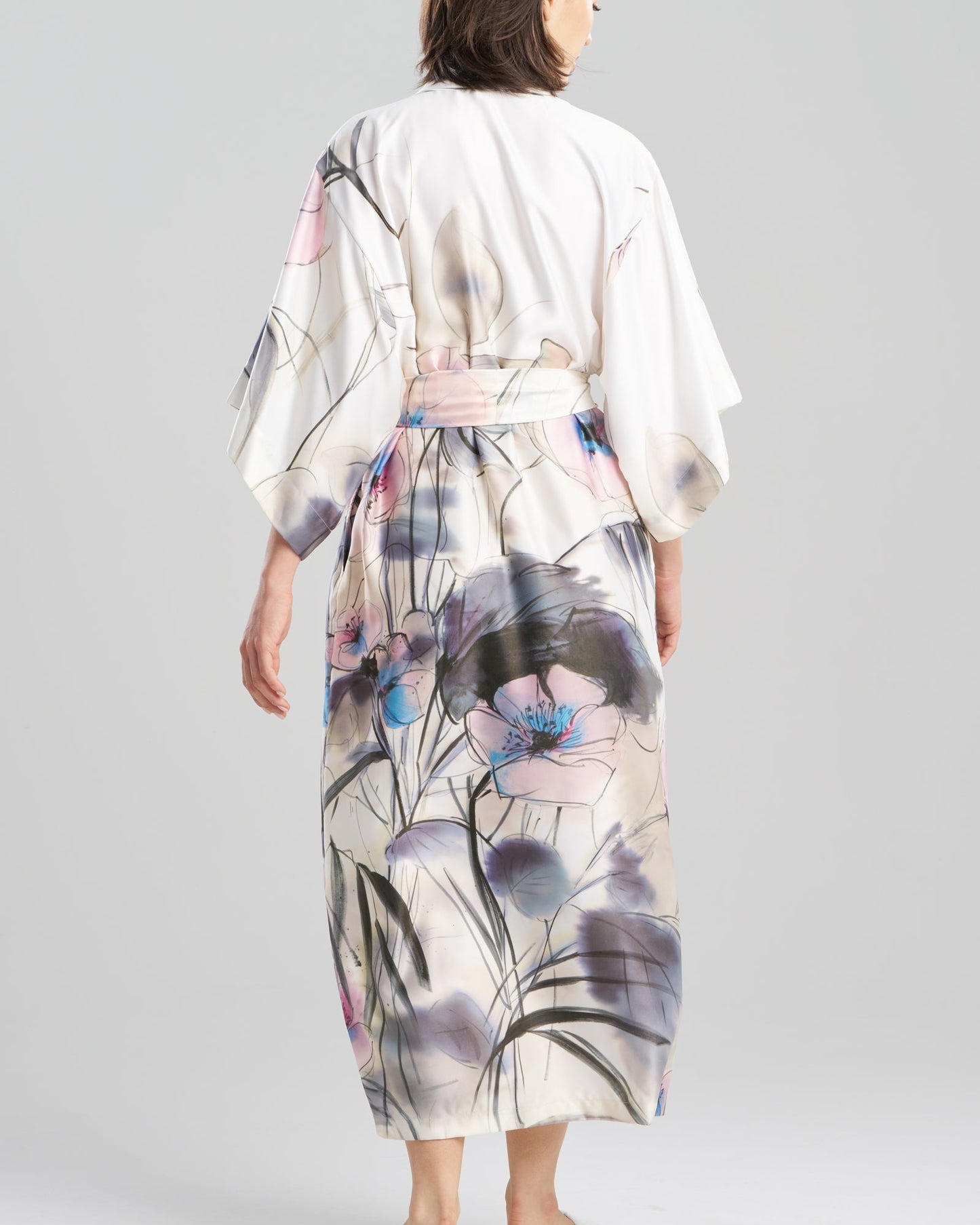 Woman wearing a floral kimono-style garment on a plain background