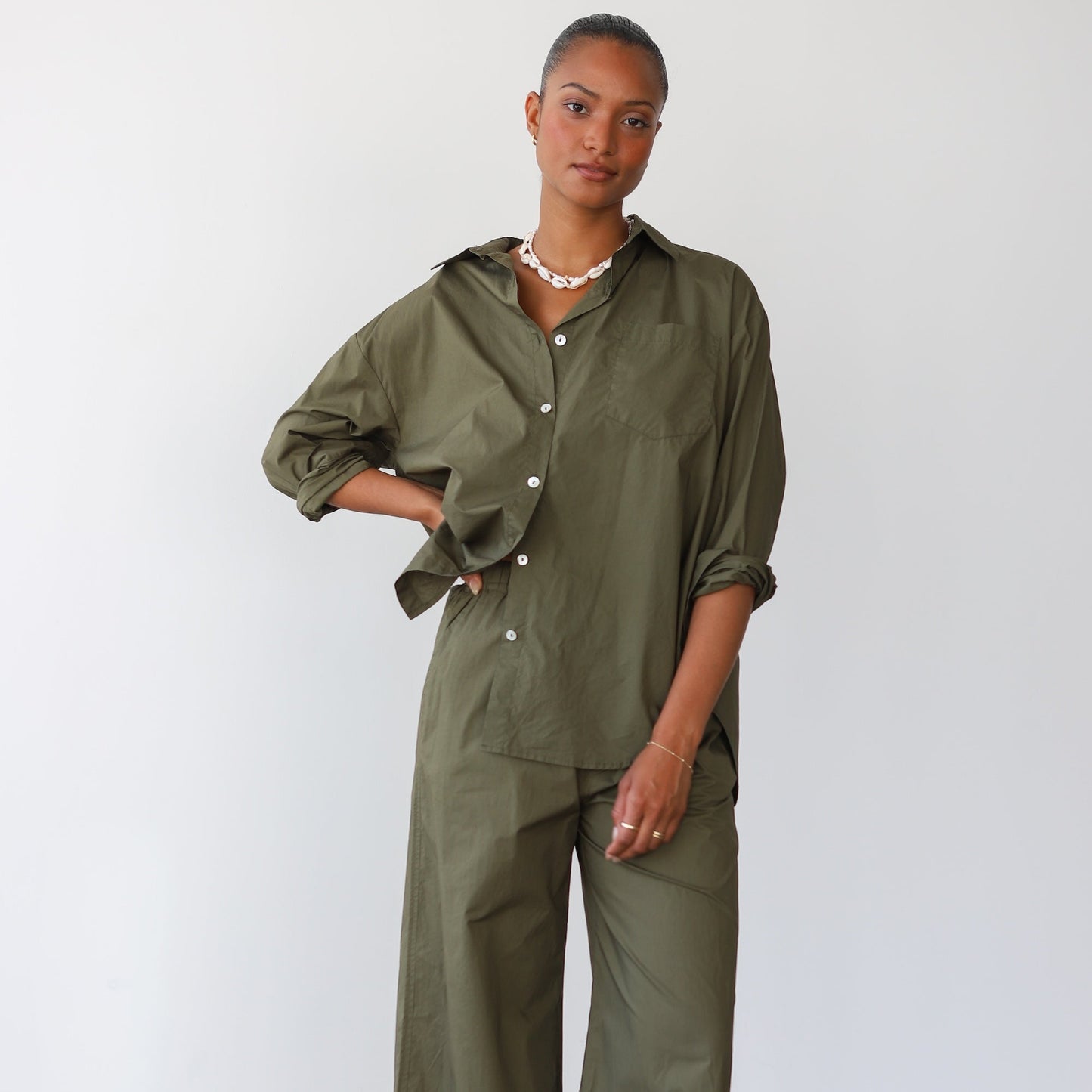 Woman wearing an olive green outfit against a white background