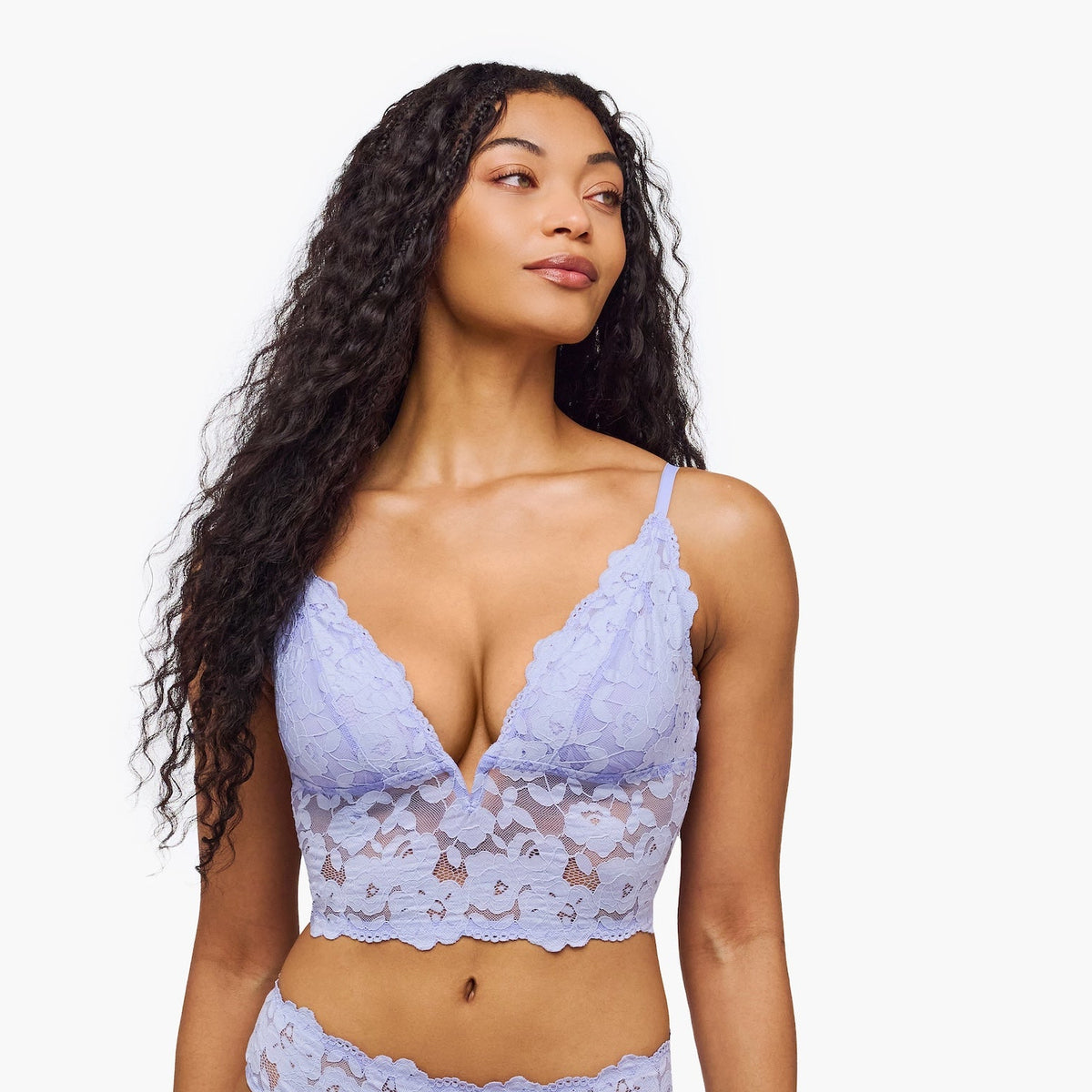 Woman wearing a light purple lace lingerie set on a white background