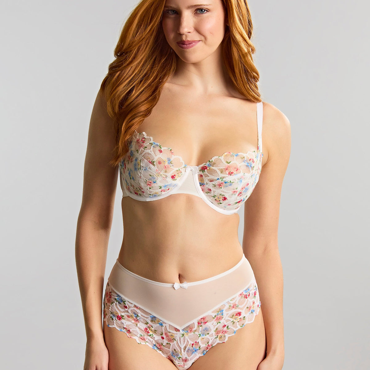 Woman wearing a floral lingerie set against a plain background