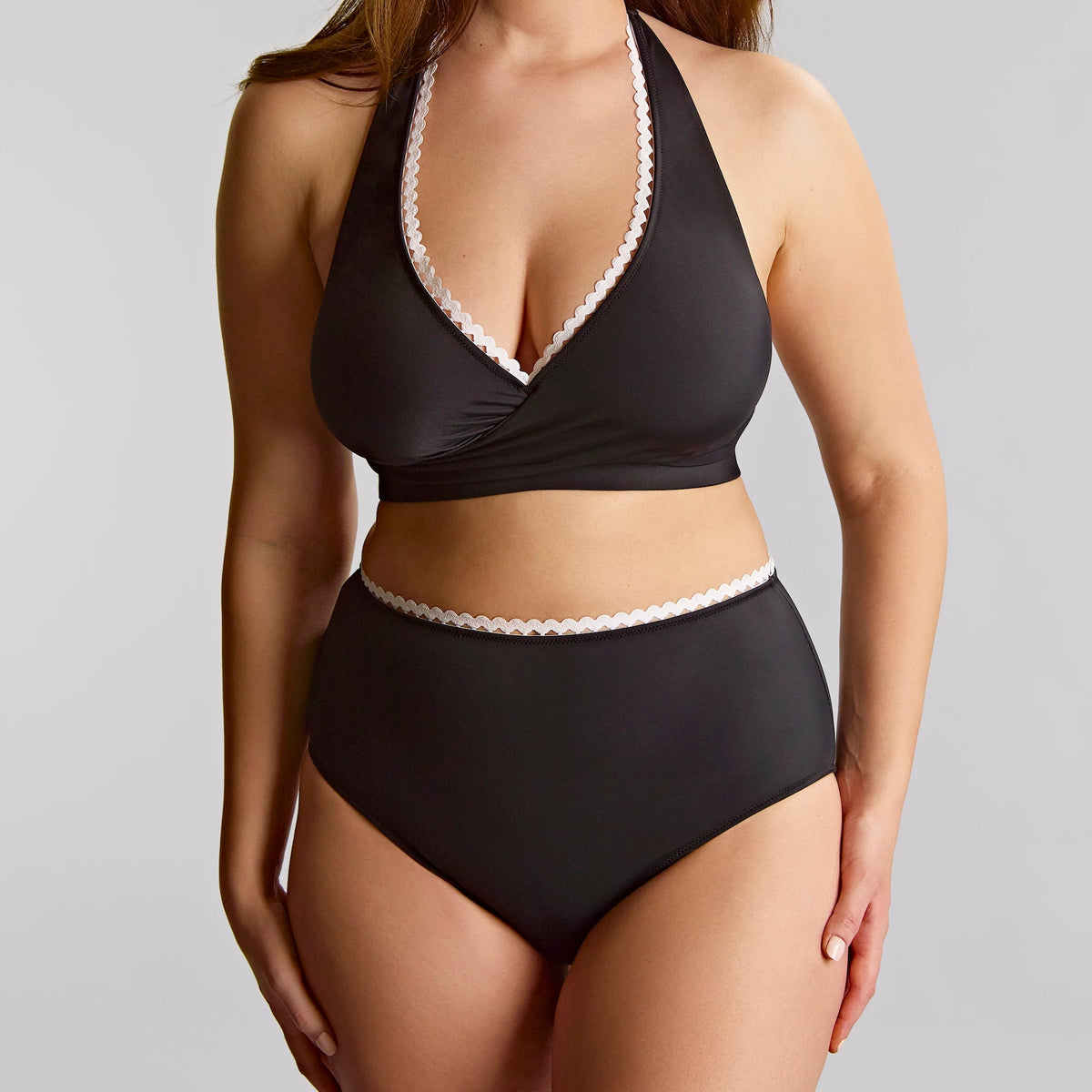 Woman wearing a black bikini with white lace trim against a plain background