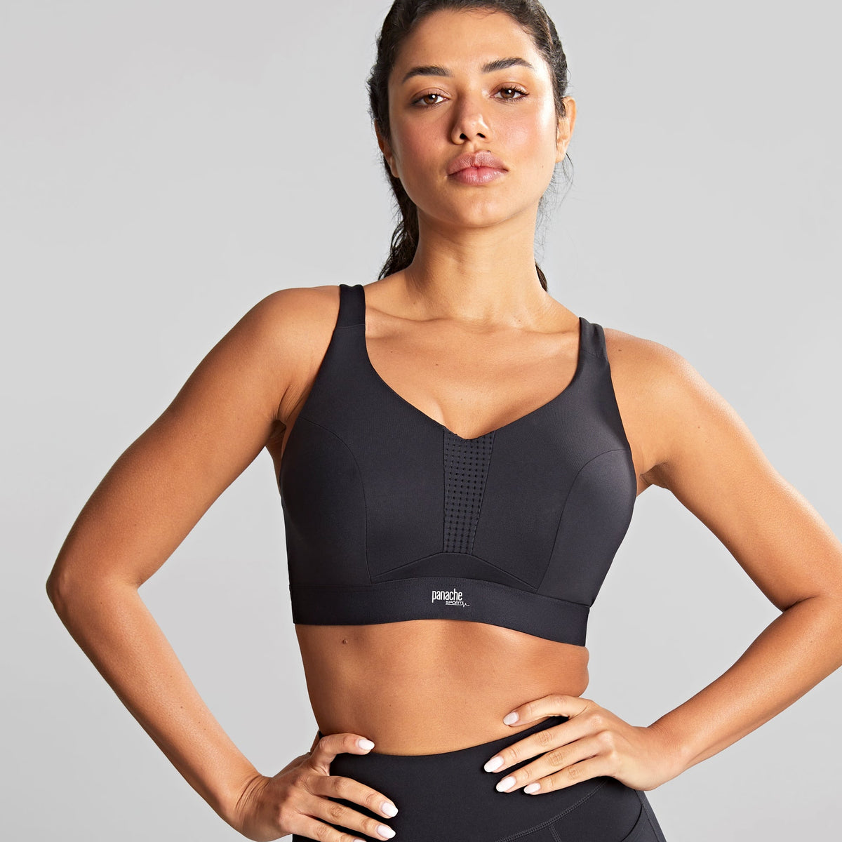 A woman wearing a black non-padded wired sports bra with a V-shaped neckline and matching black sports leggings.