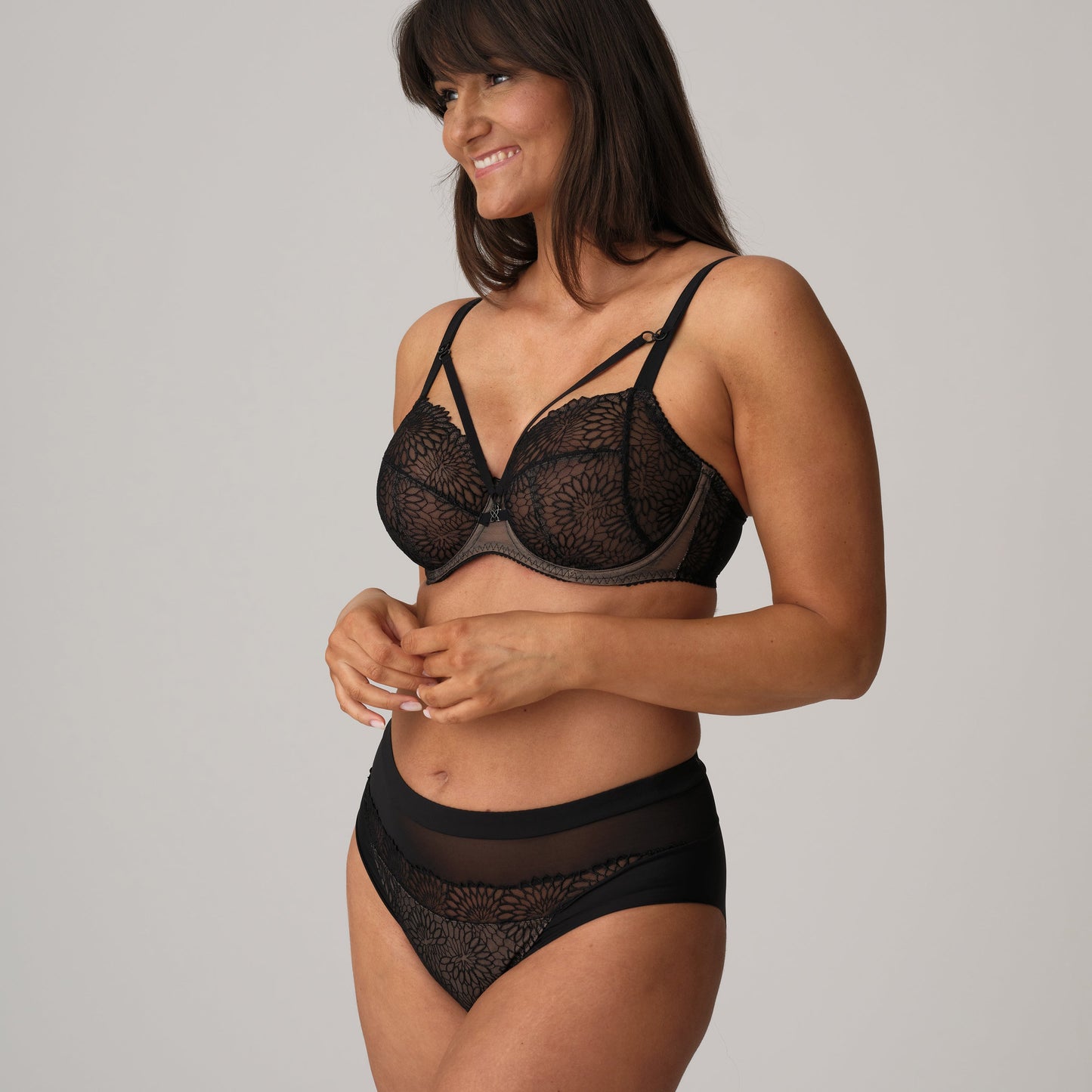Woman wearing a black lace bra and panties set on a gray background