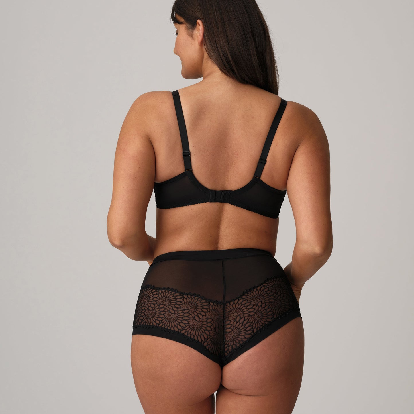 Woman wearing a black lingerie set on a plain background