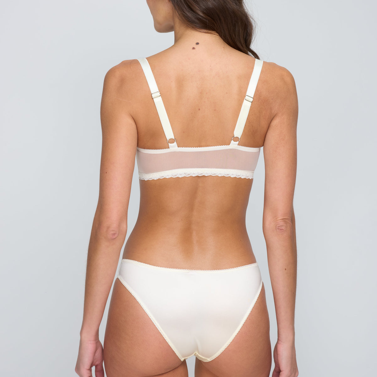 Woman wearing a white bra and panties set against a plain background