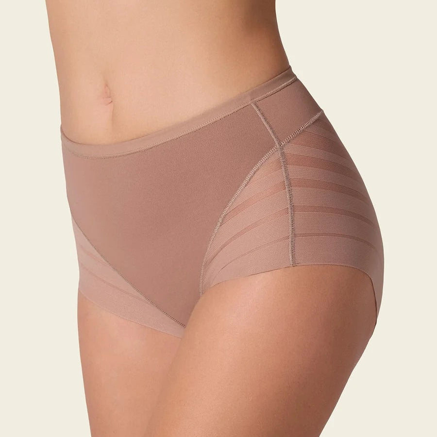 A close-up side view of a model wearing high-waisted shapewear briefs in a nude beige color with sheer mesh side panels, set against a solid off-white background.