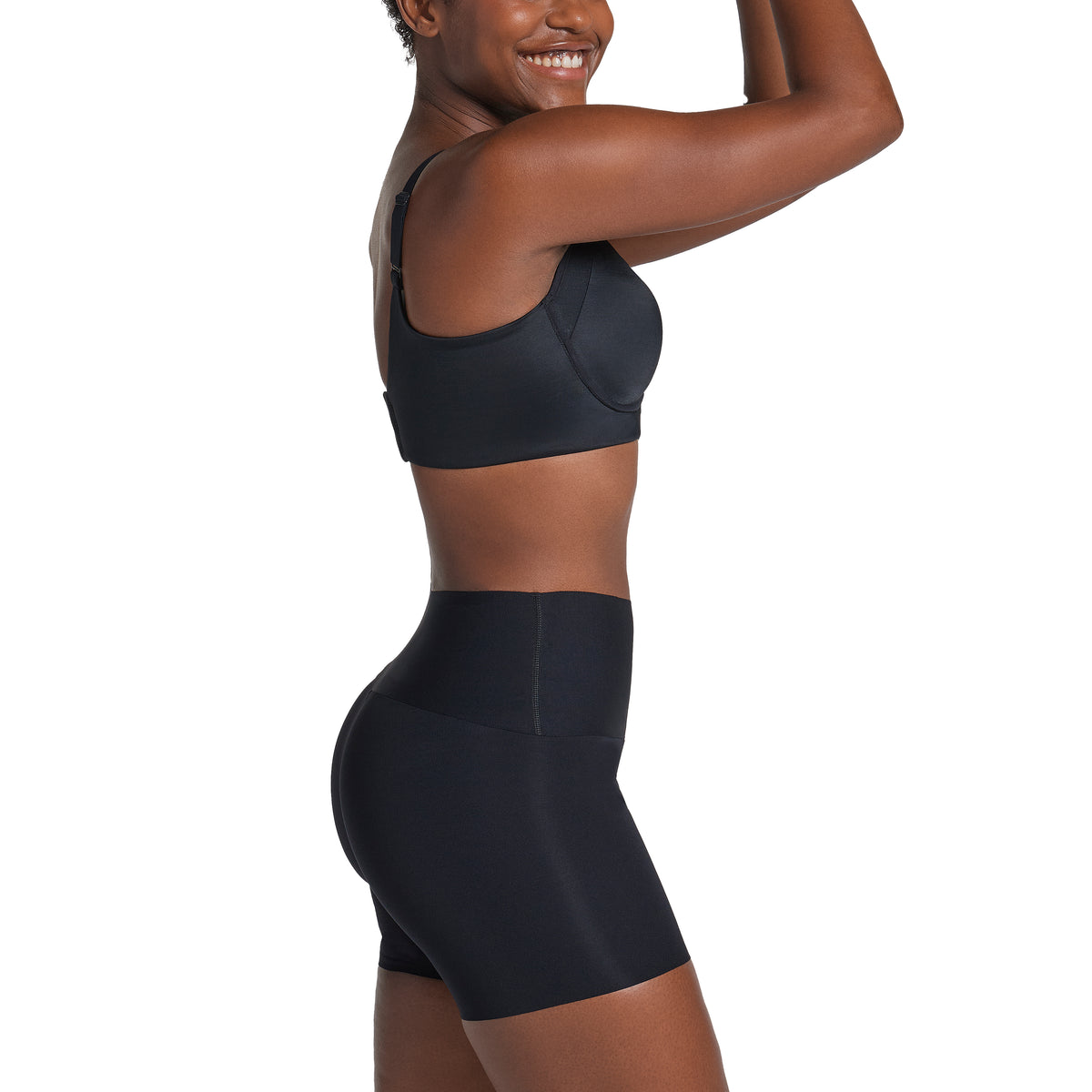 Person wearing a black sports bra and shorts on a white background