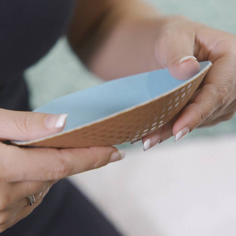 Person holding a small blue and brown item with textured surface