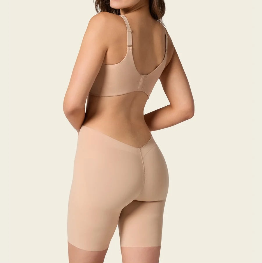 Woman wearing a beige shapewear garment on a plain background
