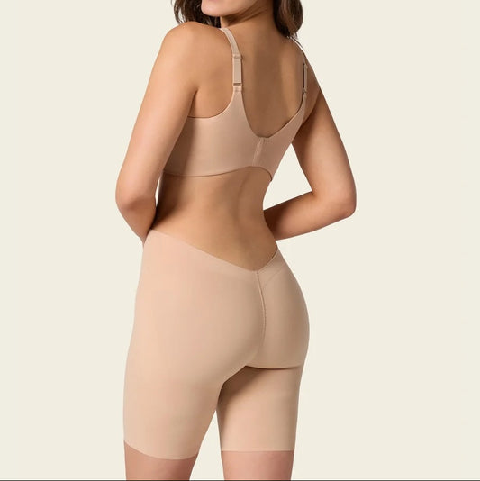 Woman wearing a beige shapewear garment on a plain background