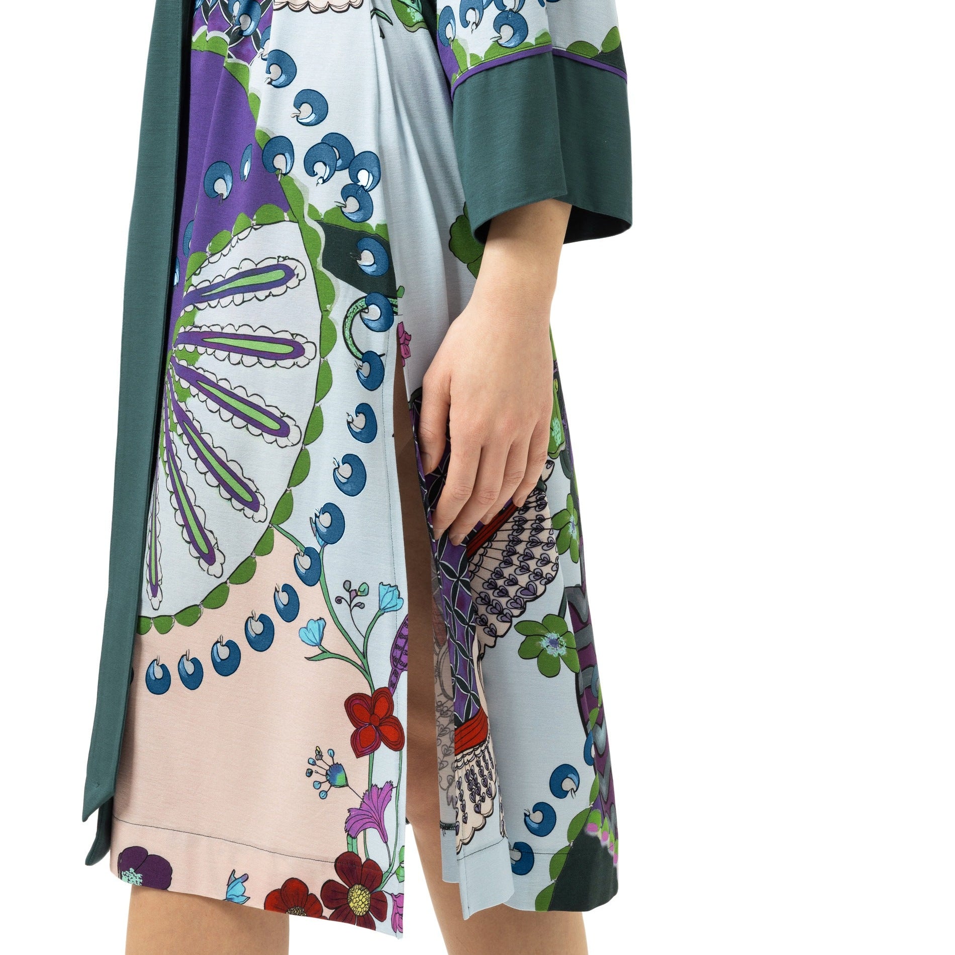 A model wearing a short kimono-style dress with a multicolor botanical and geometric print, featuring a dark green waist tie and wide sleeves, shown against a plain white background.
