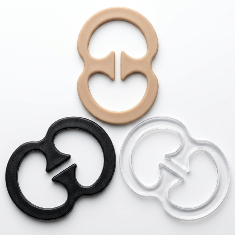 Three silicone baby teething rings in beige, black, and clear, arranged on a clean white background.