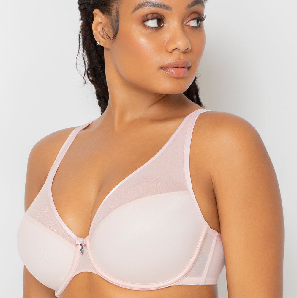 Woman wearing a light pink bra against a plain background