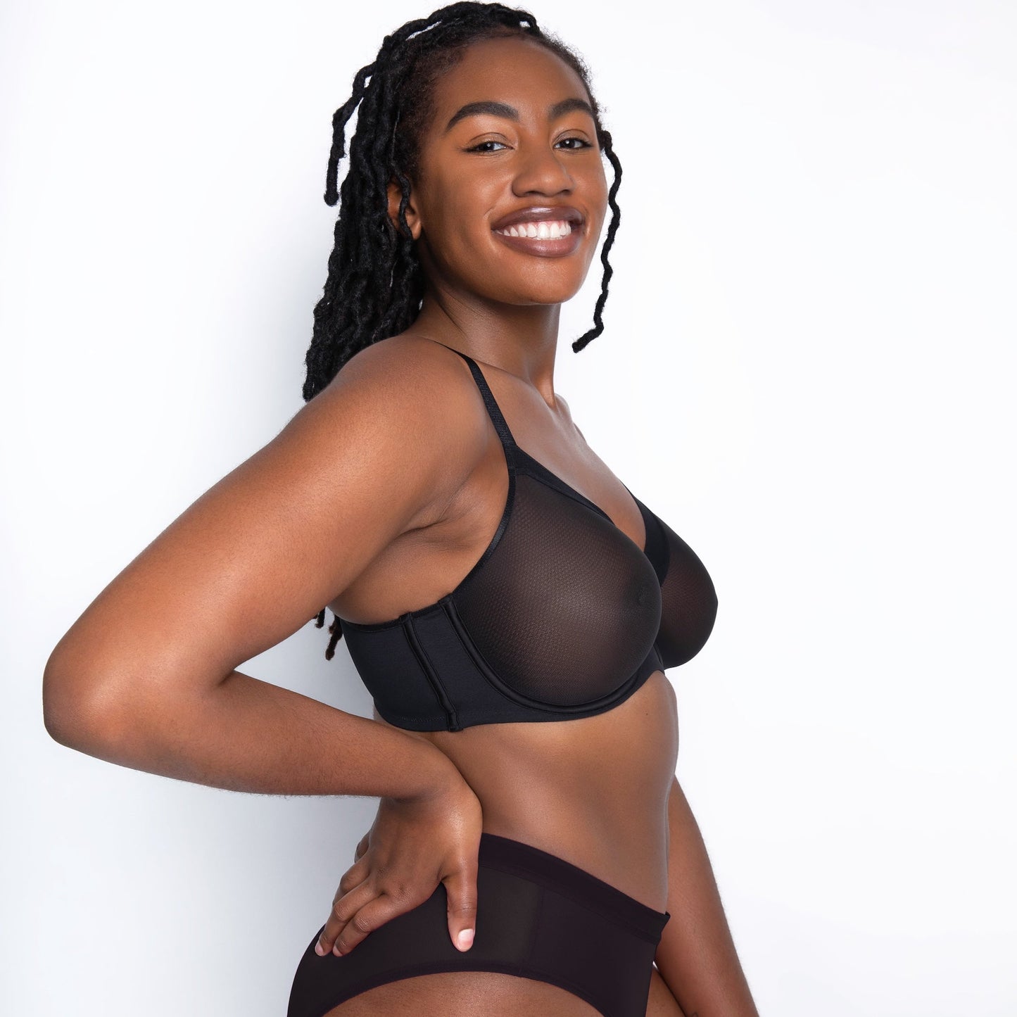 Woman wearing a black sheer bikini against a white background