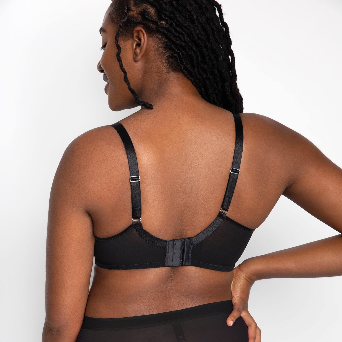 Person wearing a black bra and underwear set on a white background