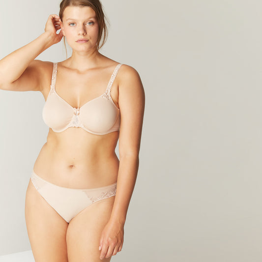 Woman wearing a beige bra and panties set against a plain background
