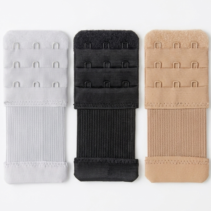 Three bra hook-and-loop fastener panels in white, black, and nude beige, arranged vertically side-by-side on a clean white background.