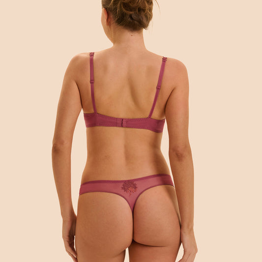 Woman wearing a maroon bra and panties set on a beige background
