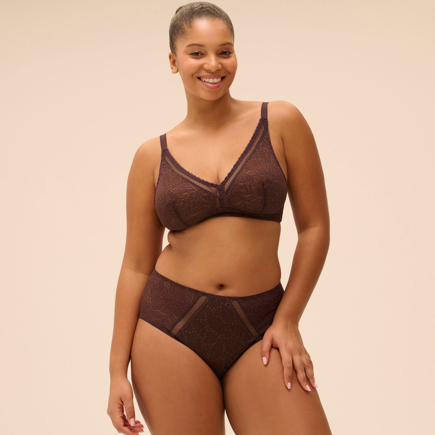 Woman wearing a brown bra and panties set on a beige background