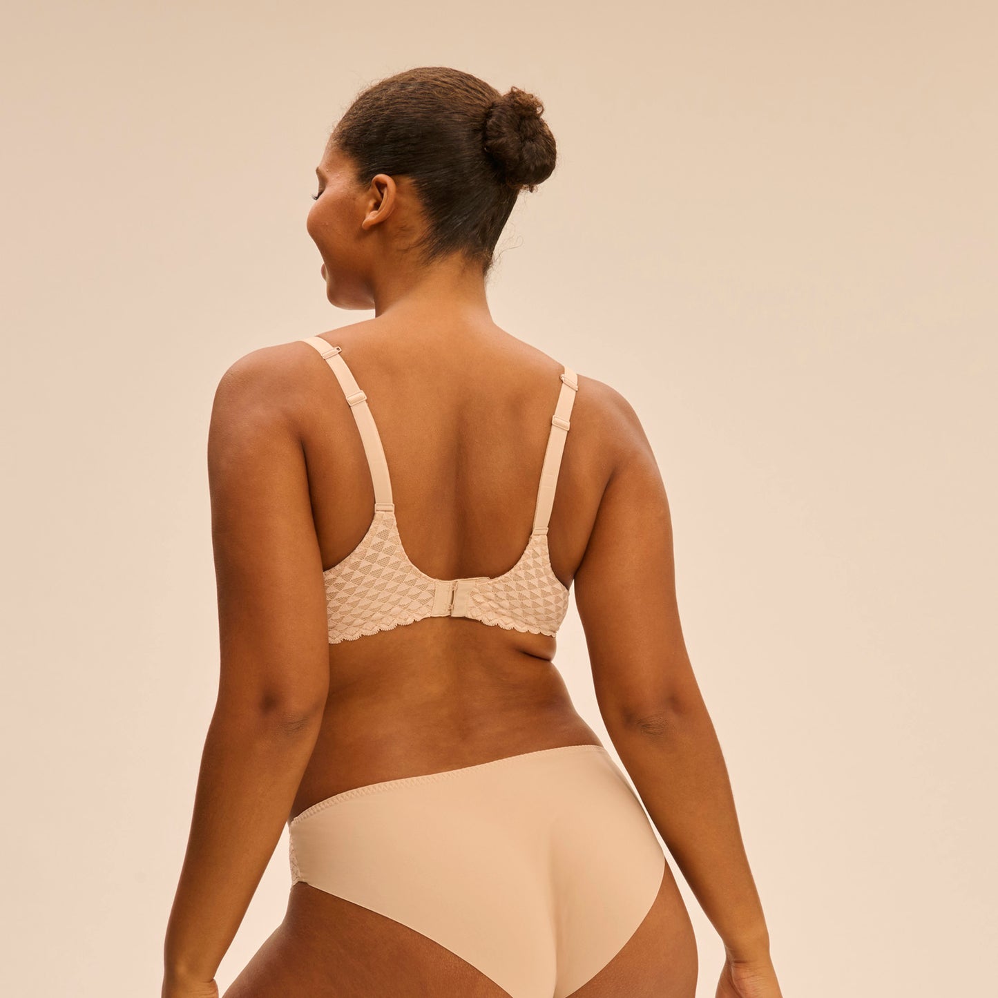 Woman wearing a beige bikini set against a plain background