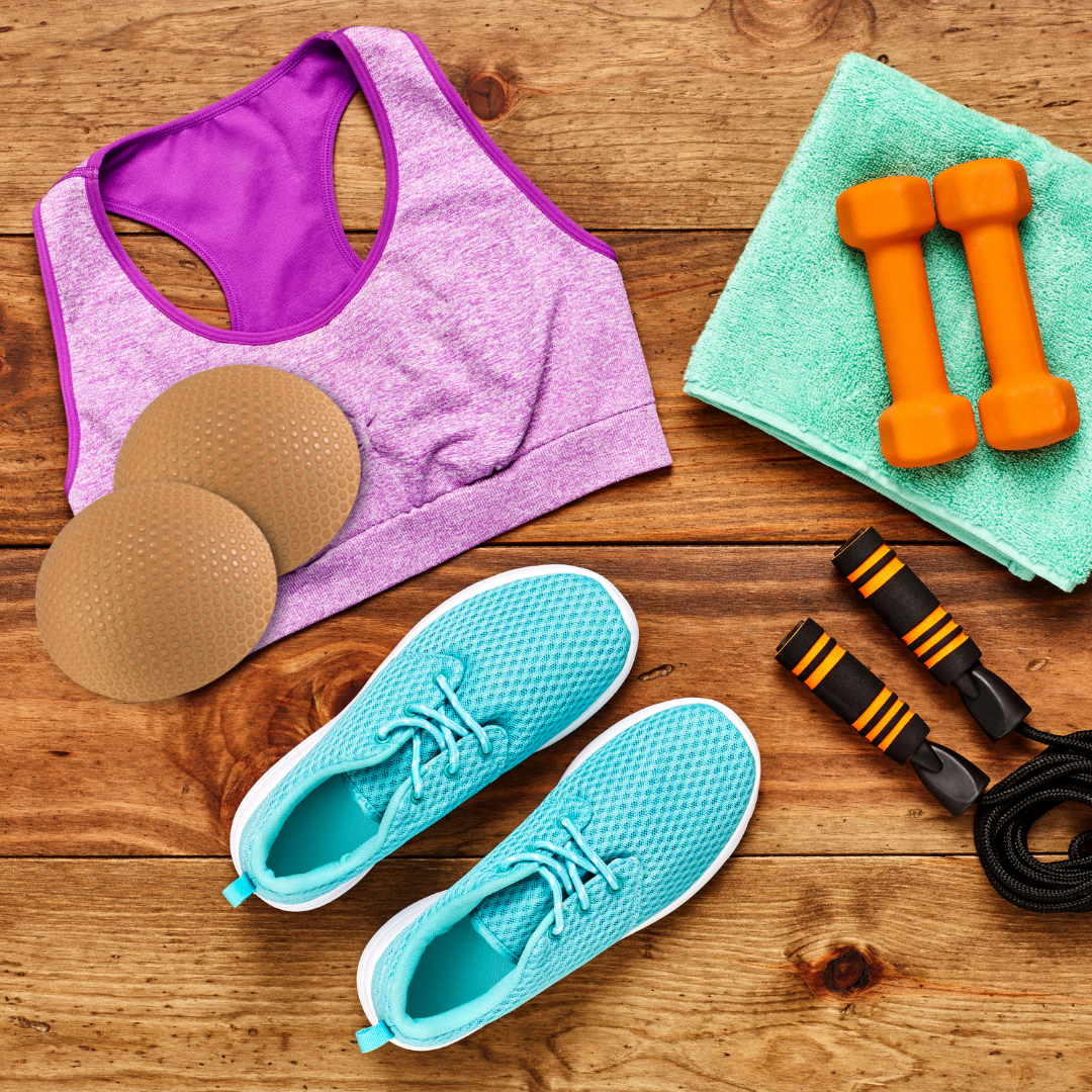 Fitness items including a sports bra, sneakers, dumbbells, and jump rope on a wooden surface.