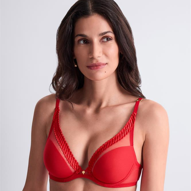 Woman wearing a red bra against a plain background