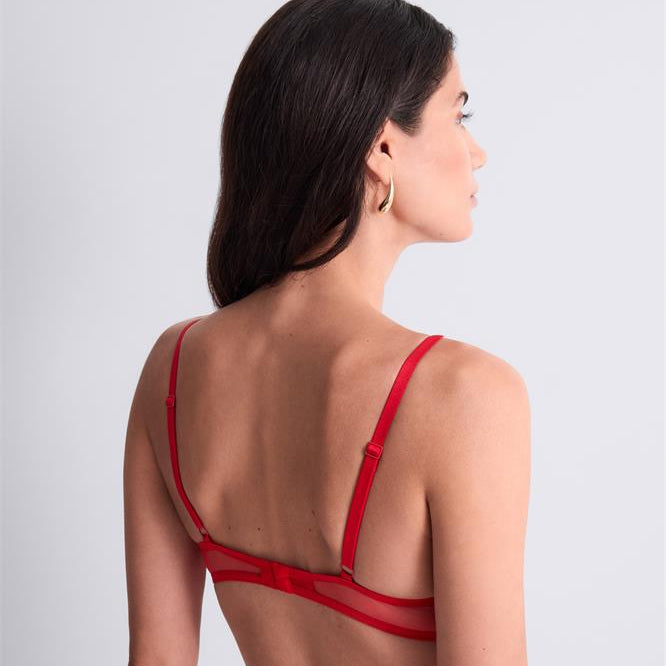 Woman wearing a red bralette against a light gray background