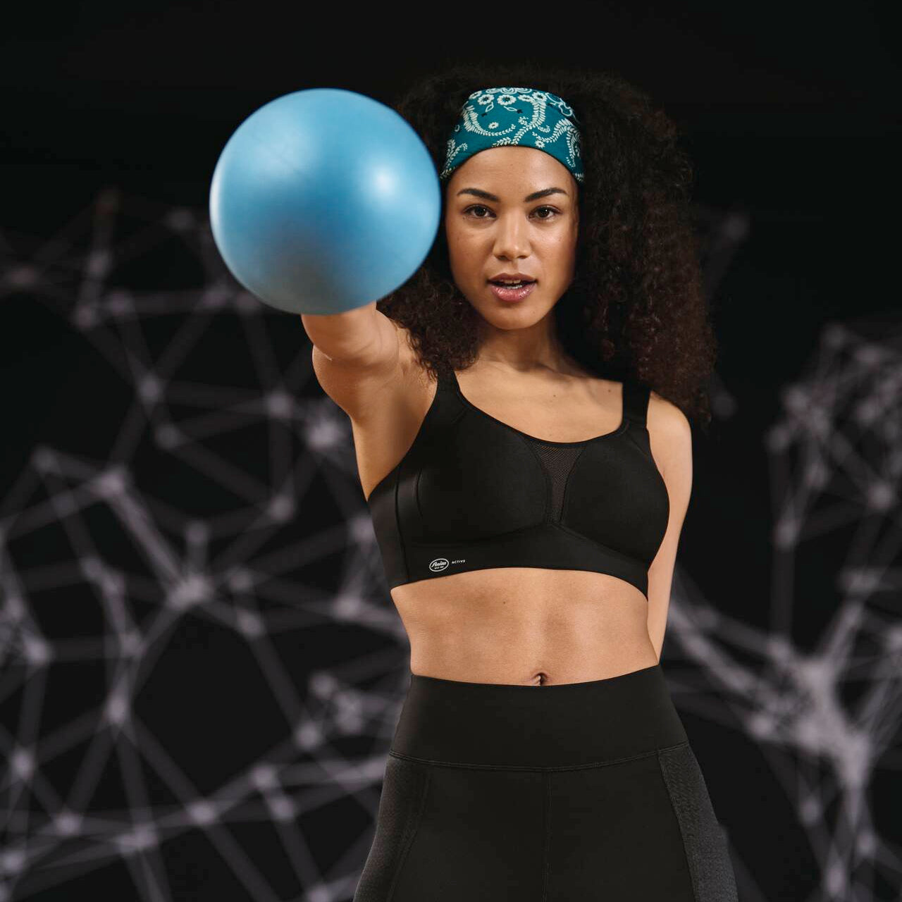 Woman holding a blue medicine ball against a dark background