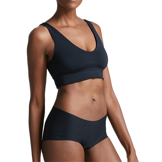 Person wearing a black bralette and shorts on a white background