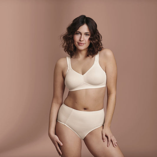 Woman wearing a white bra and panties set against a brown background