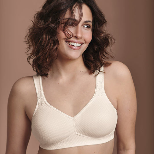 Woman wearing a beige bra and panties set against a brown background