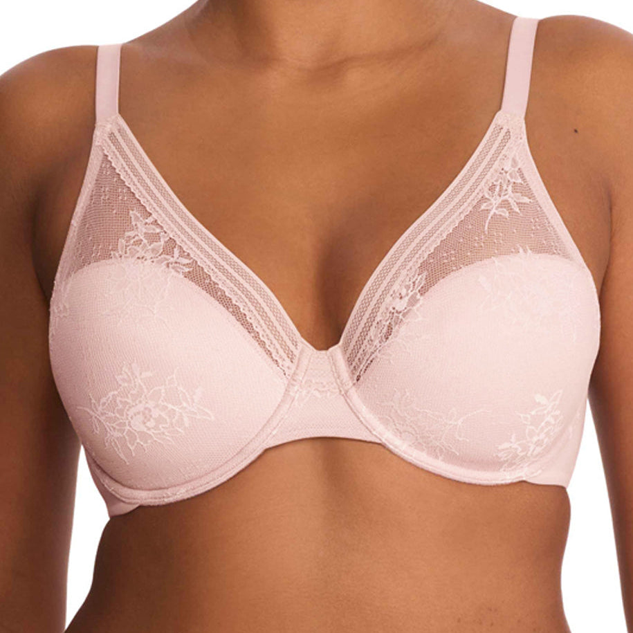 A close-up of a model wearing a light pink underwire bra with floral lace detailing and thin shoulder straps, paired with matching lace panties against a plain white background.