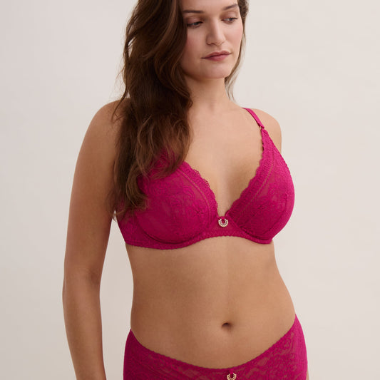 Woman wearing a pink bra and underwear set on a plain background