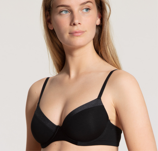 Woman wearing a black bra against a plain background