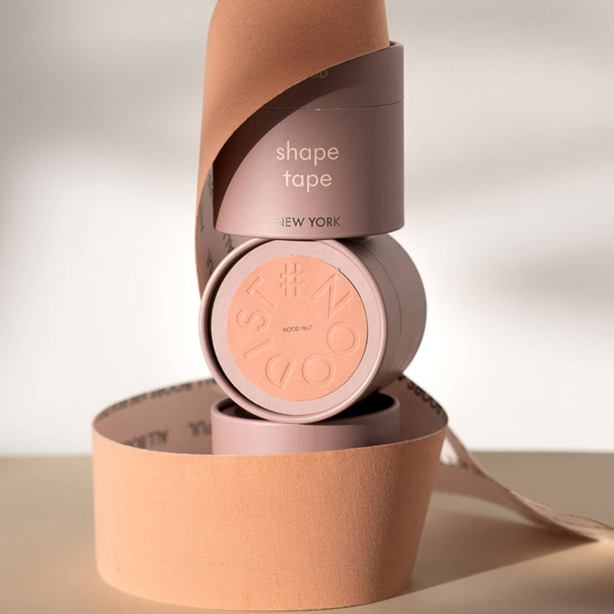 Pink shape tape with packaging on a neutral background
