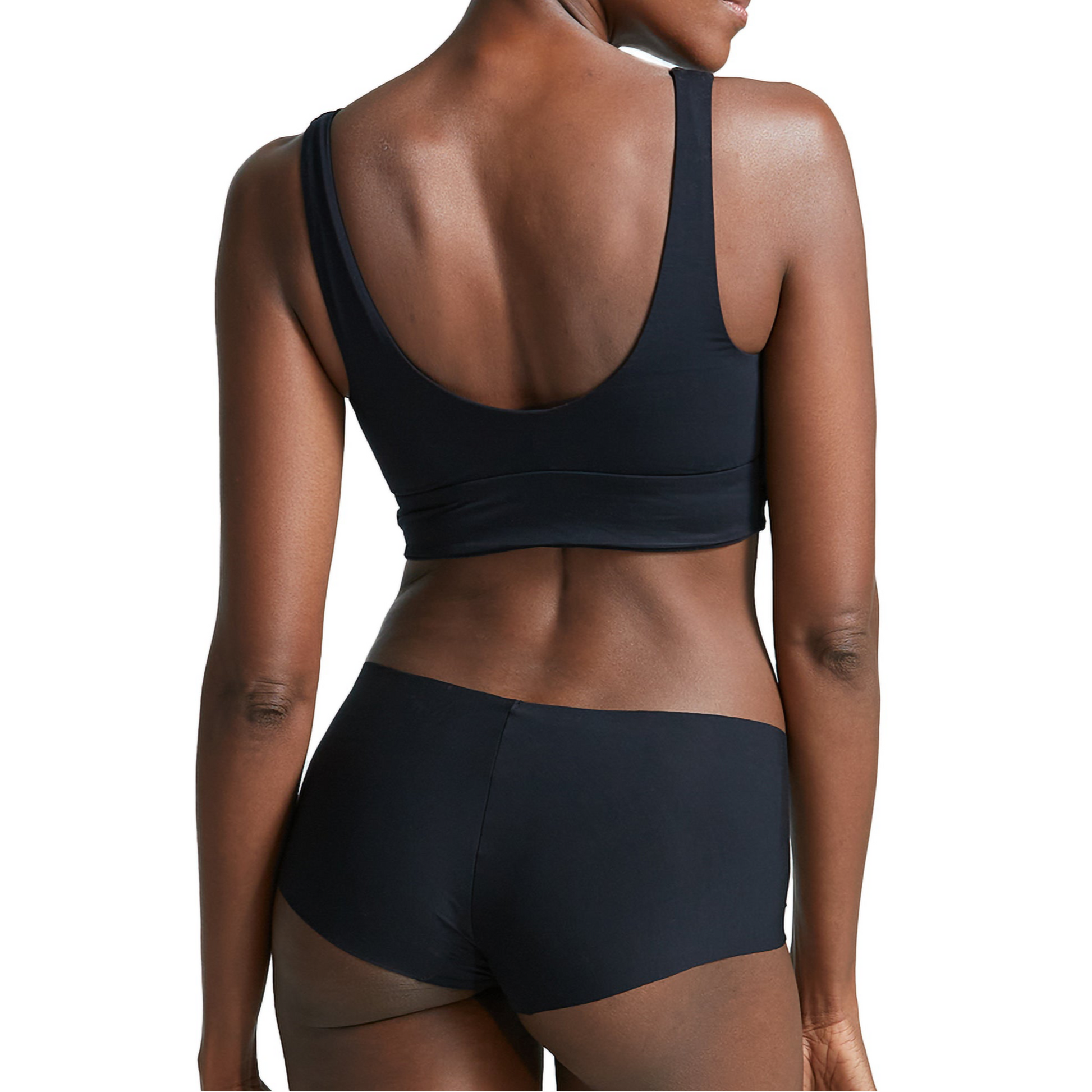 Person wearing a black bralette and shorts set on a white background