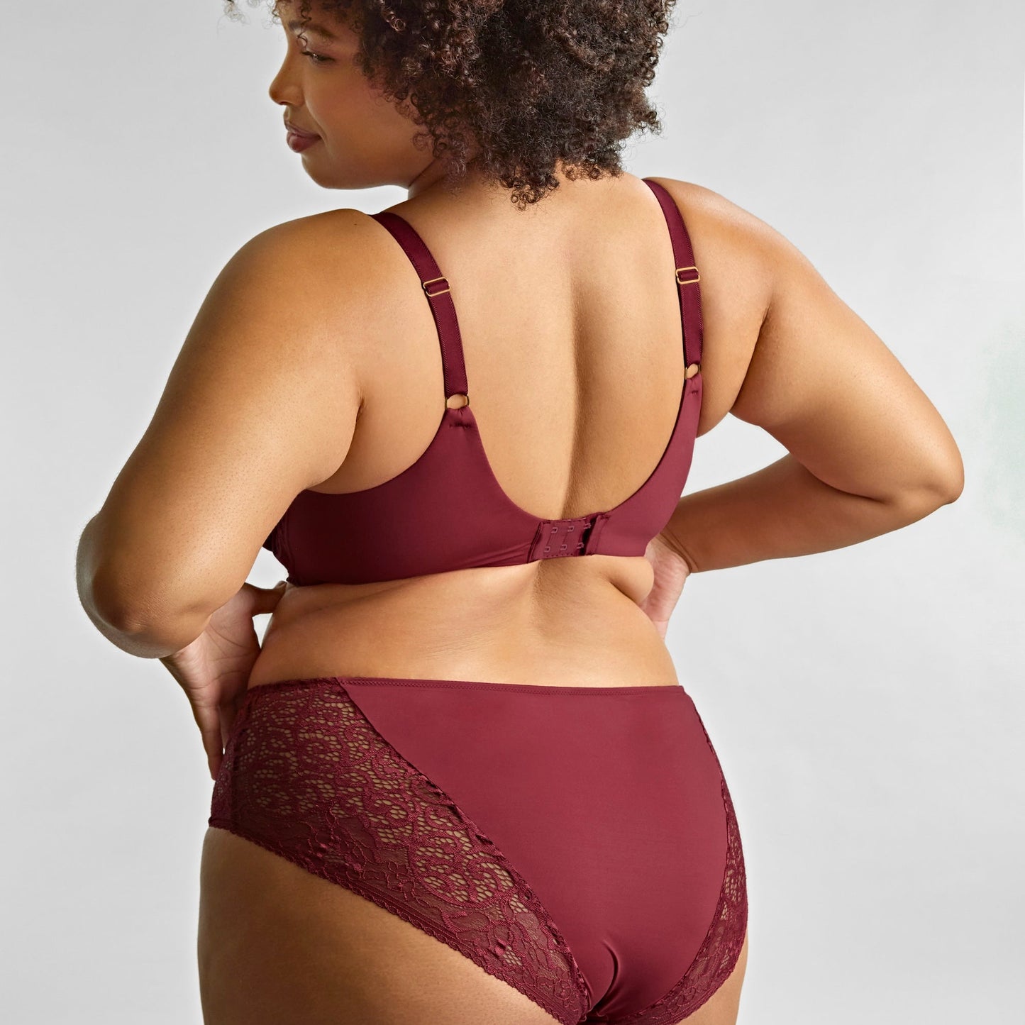 Woman wearing a burgundy lingerie set on a plain background