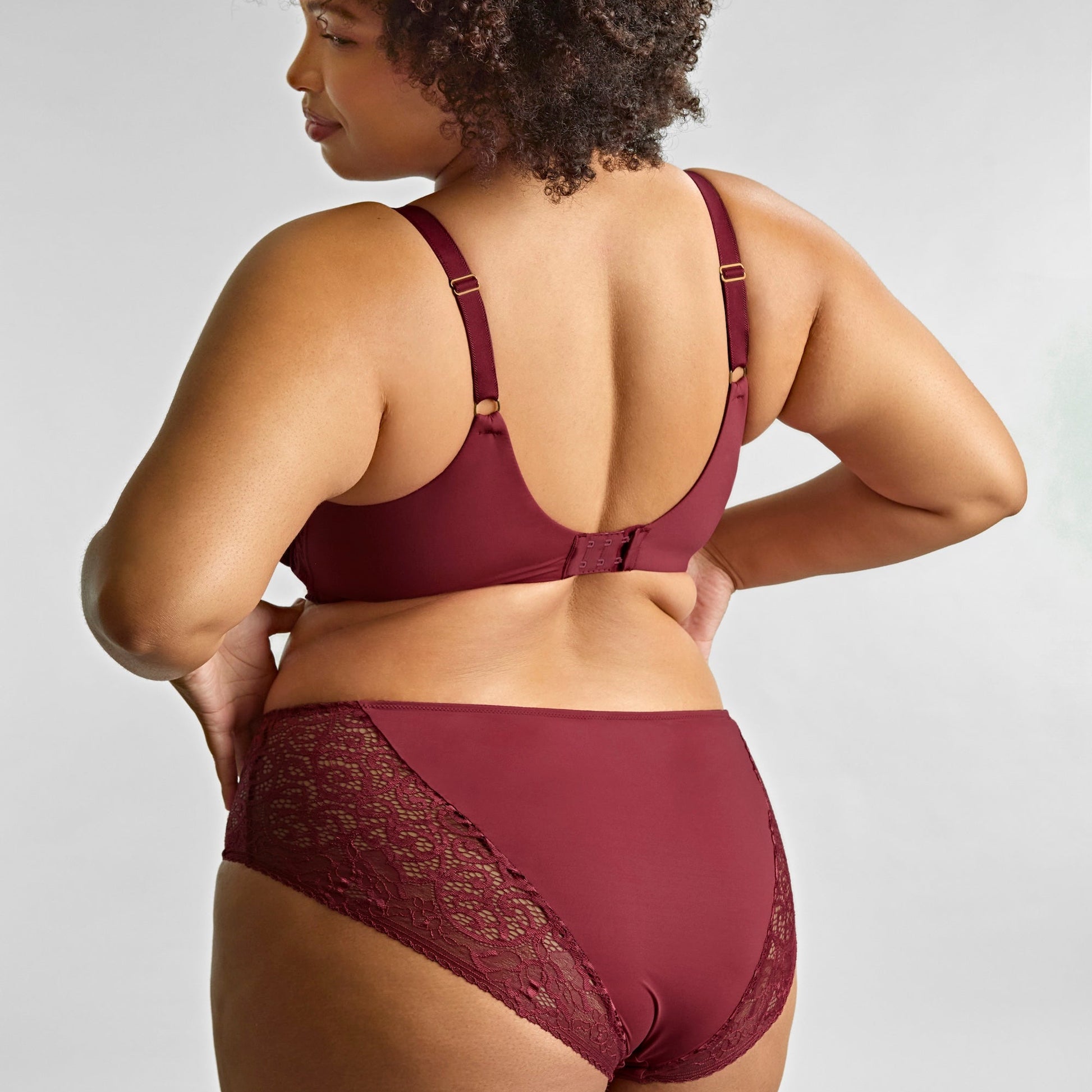 Woman wearing a burgundy lingerie set on a plain background